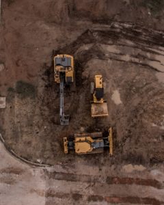 three construction machines on dirt aerial view